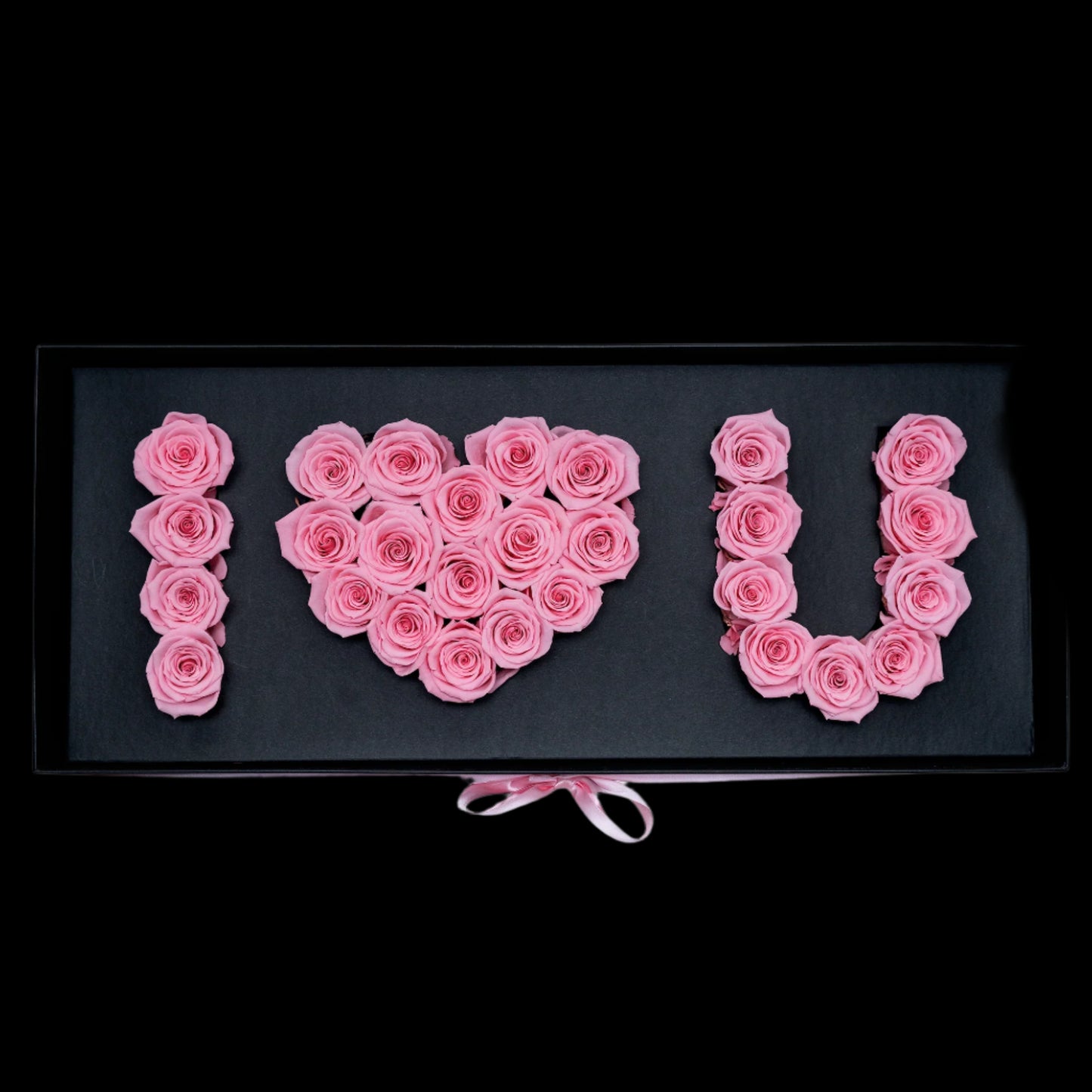 Pink roses arranged to spell 'I ❤️ U' on a black background
