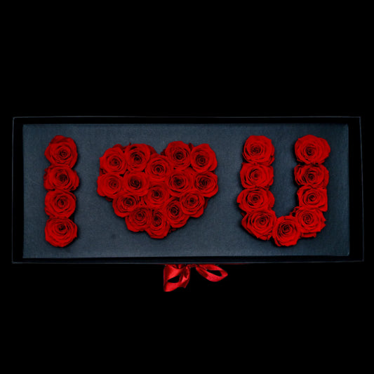 Floral arrangement spelling 'I § U' with red roses on a black background